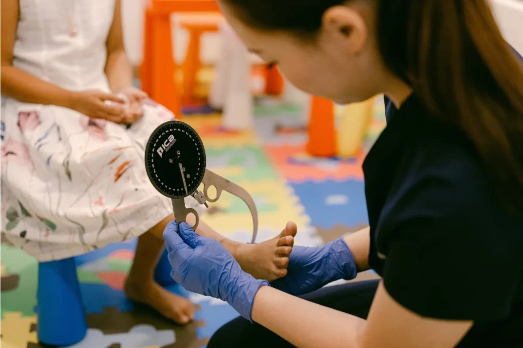 Podiatrist measuring child's flat foot using goniometer