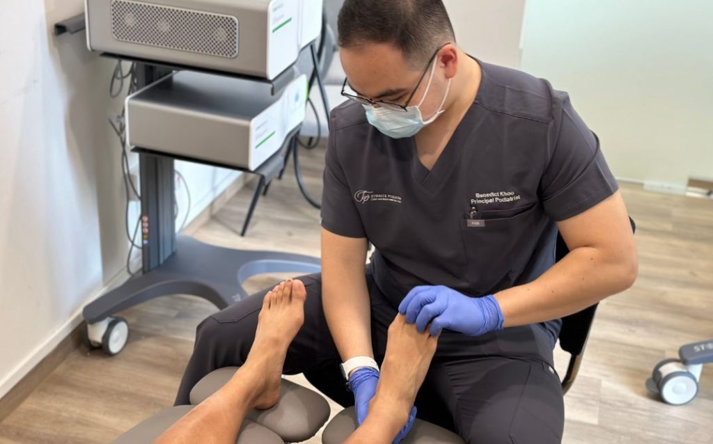 Rawatan sakit tumit di Singapura. Gambar menunjukkan podiatrist di Straits podiatry menyediakan rawatan untuk sakit tumit kepada seorang pesakit di Singapura.