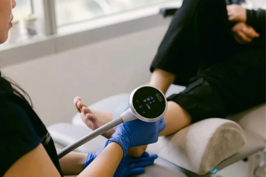 podiatrist performing shockwave therapy on a left lateral ankle