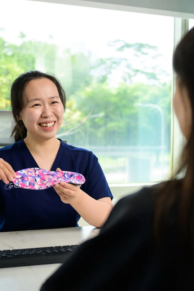 Singapore Podiatrist Michelle Goh showing patient a custom orthotic during consultation