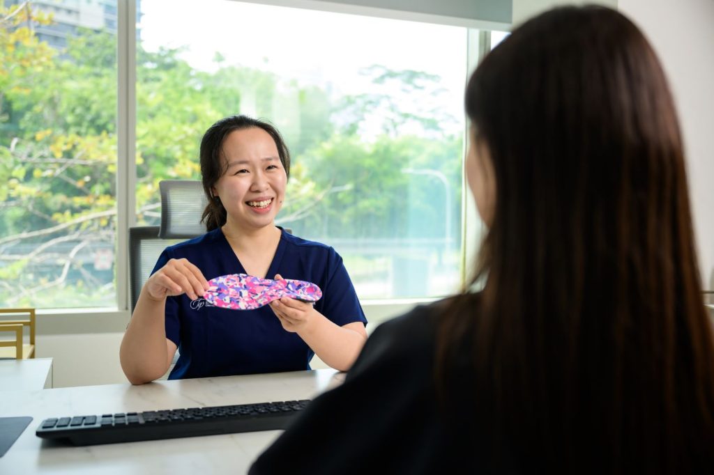 Podiatrist Michelle Goh educating patients on custom orthotics in Singapore