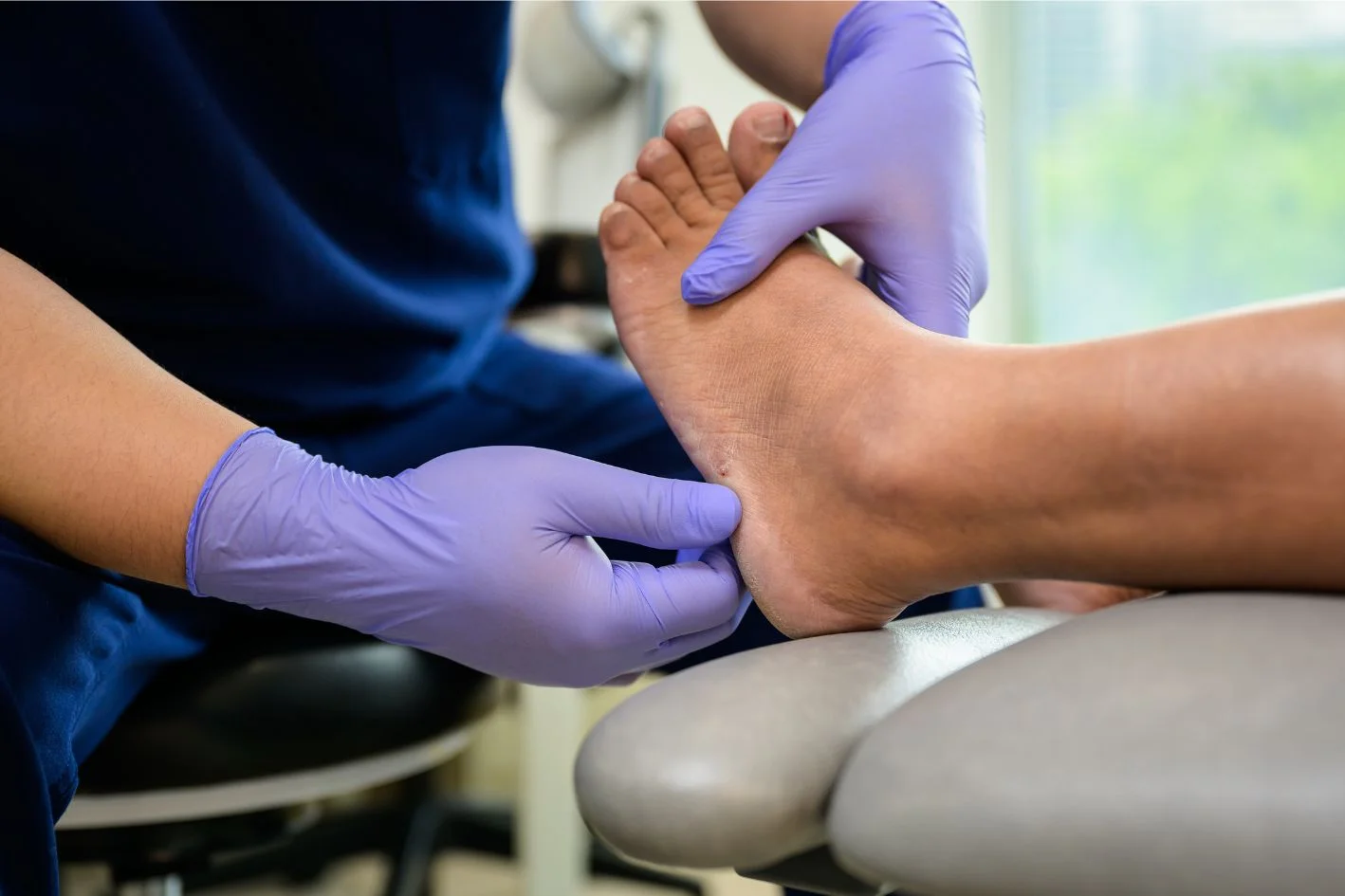 Podiatrist in Singapore assessing a patient's left foot for peroneal tendonitis